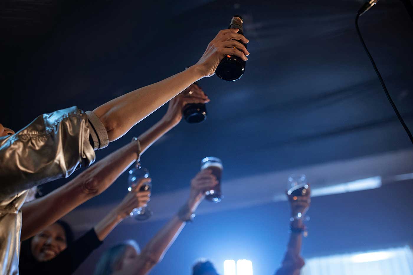 Party scene arms holding drinks in a bar