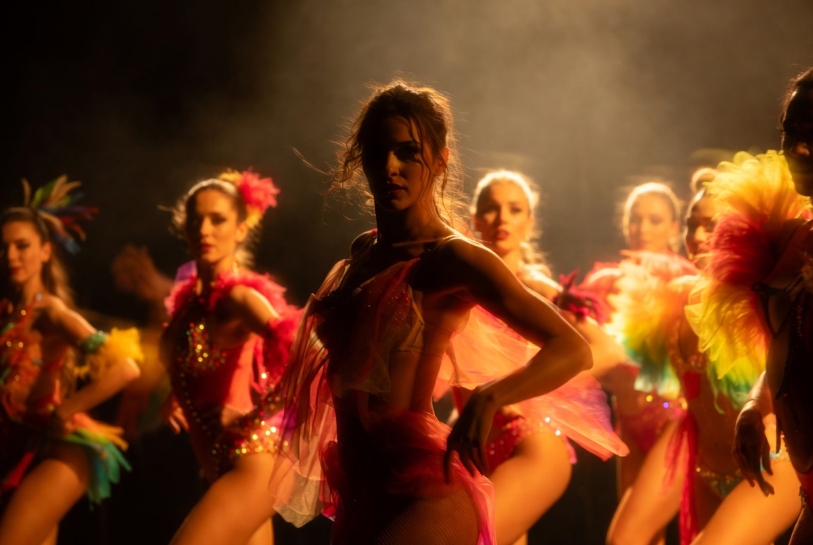 Dancers on stage in colourful costumes, moody lighting